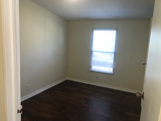 302 North Burnet Street Bremond, TX 76629 - Photo 15 of 41 an empty room with wooden floor and windows