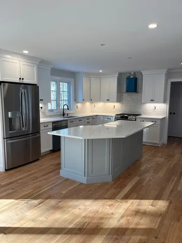 a kitchen with stainless steel appliances granite countertop a stove top oven a sink and a refrigerator