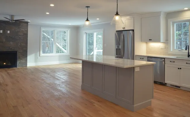 a large kitchen with granite countertop a stove a sink a refrigerator and a wooden floor