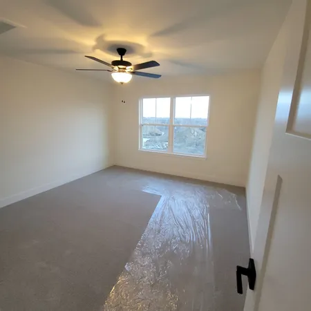 an empty room with windows and fan