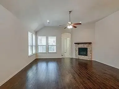 an empty room with wooden floor fan and windows