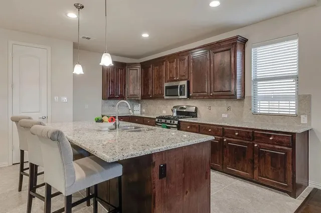 a kitchen with kitchen island granite countertop a stove sink microwave and cabinets