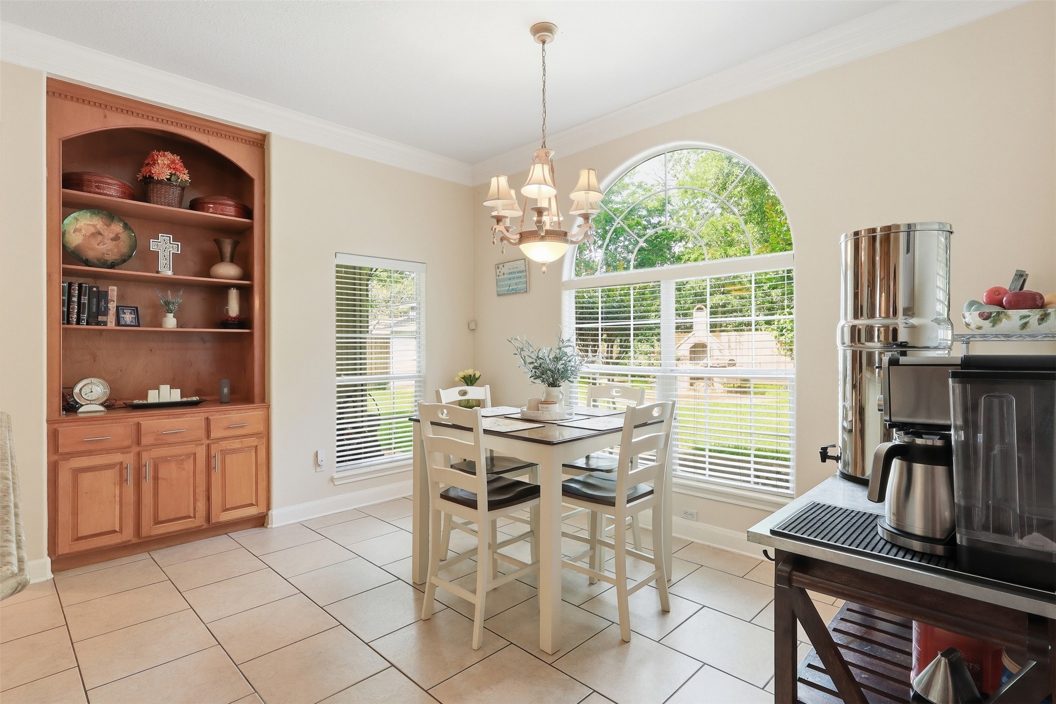 21411 Stargrass Drive Spring, TX 77388 - Photo 11 of 24 Charming breakfast nook filled with natural light from a large arched window. The space features a custom built-in hutch with ample storage and display shelving, perfect for morning coffee and casual meals.
