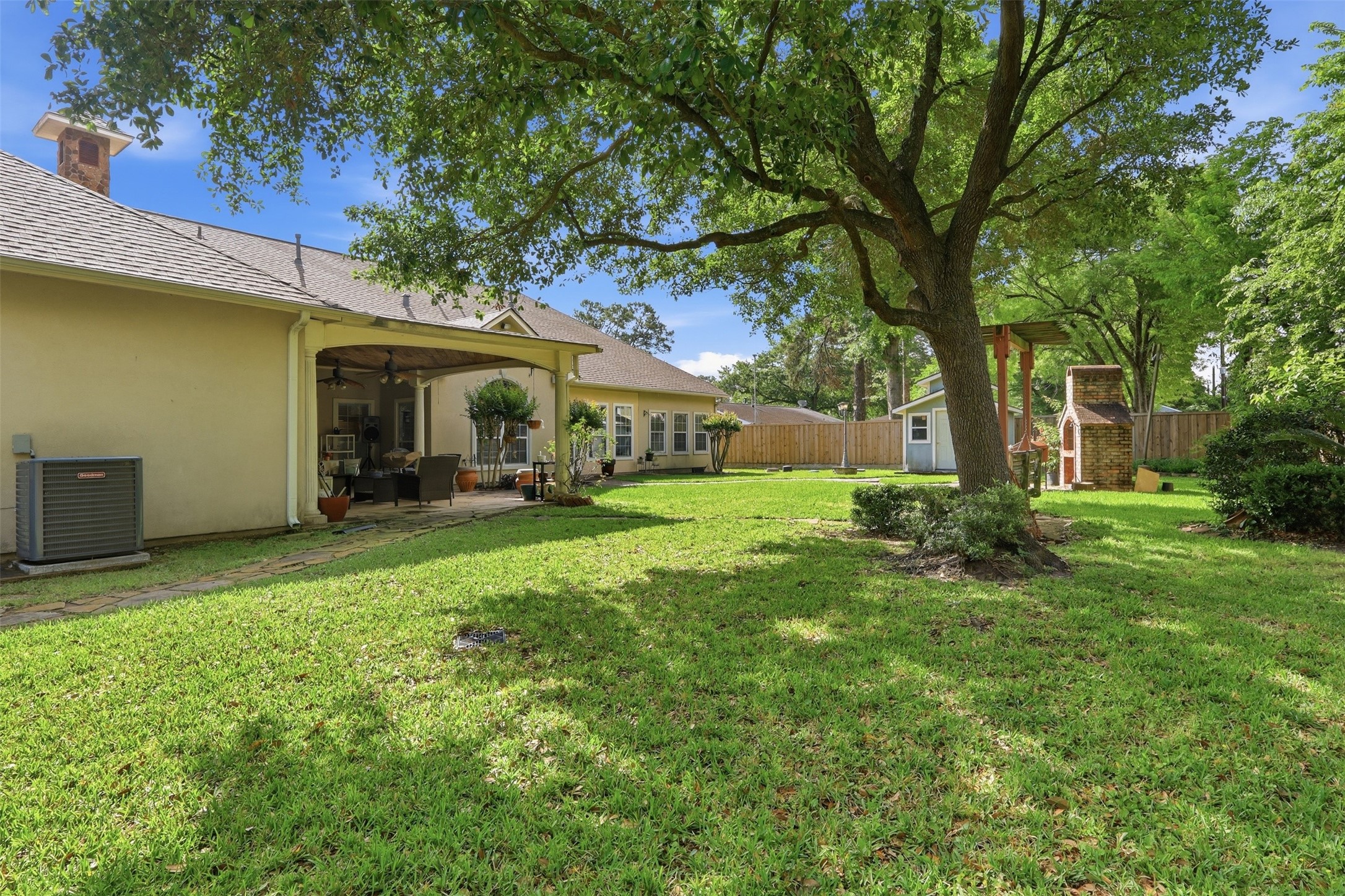 21411 Stargrass Drive Spring, TX 77388 - Photo 20 of 24 Expansive backyard retreat with a covered patio, custom outdoor fireplace, storage shed and a decorative pergola providing a serene shaded spot by the trees.