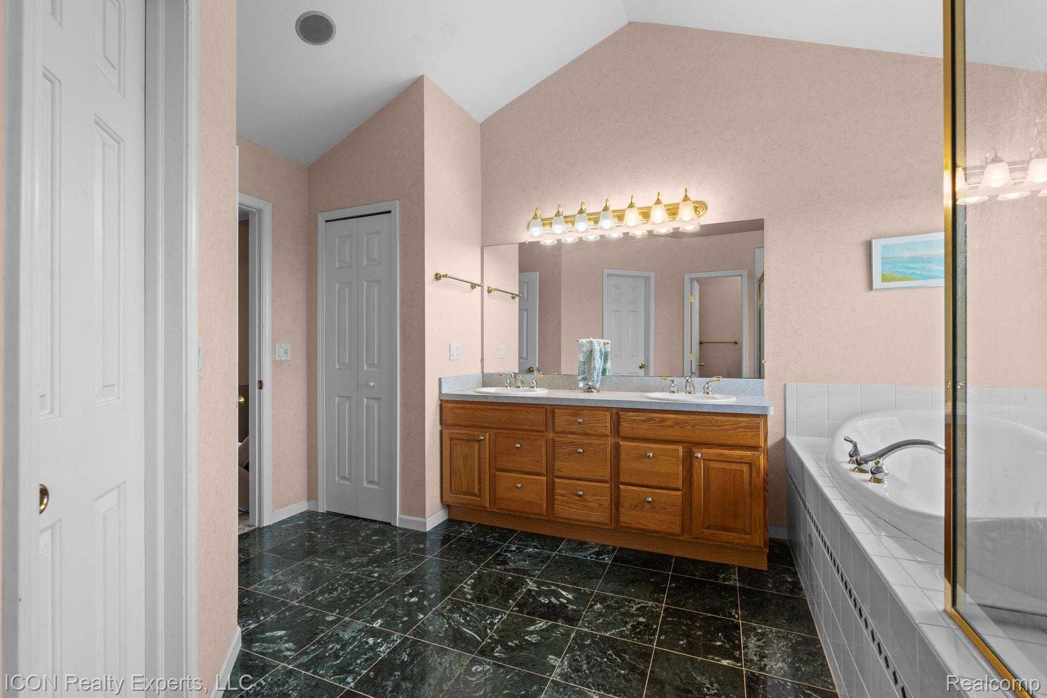 5128 Baldwin Road Metamora, MI 48455 - Photo 33 of 68 Full bathroom with double vanity, a bath, vaulted ceiling, and a closet