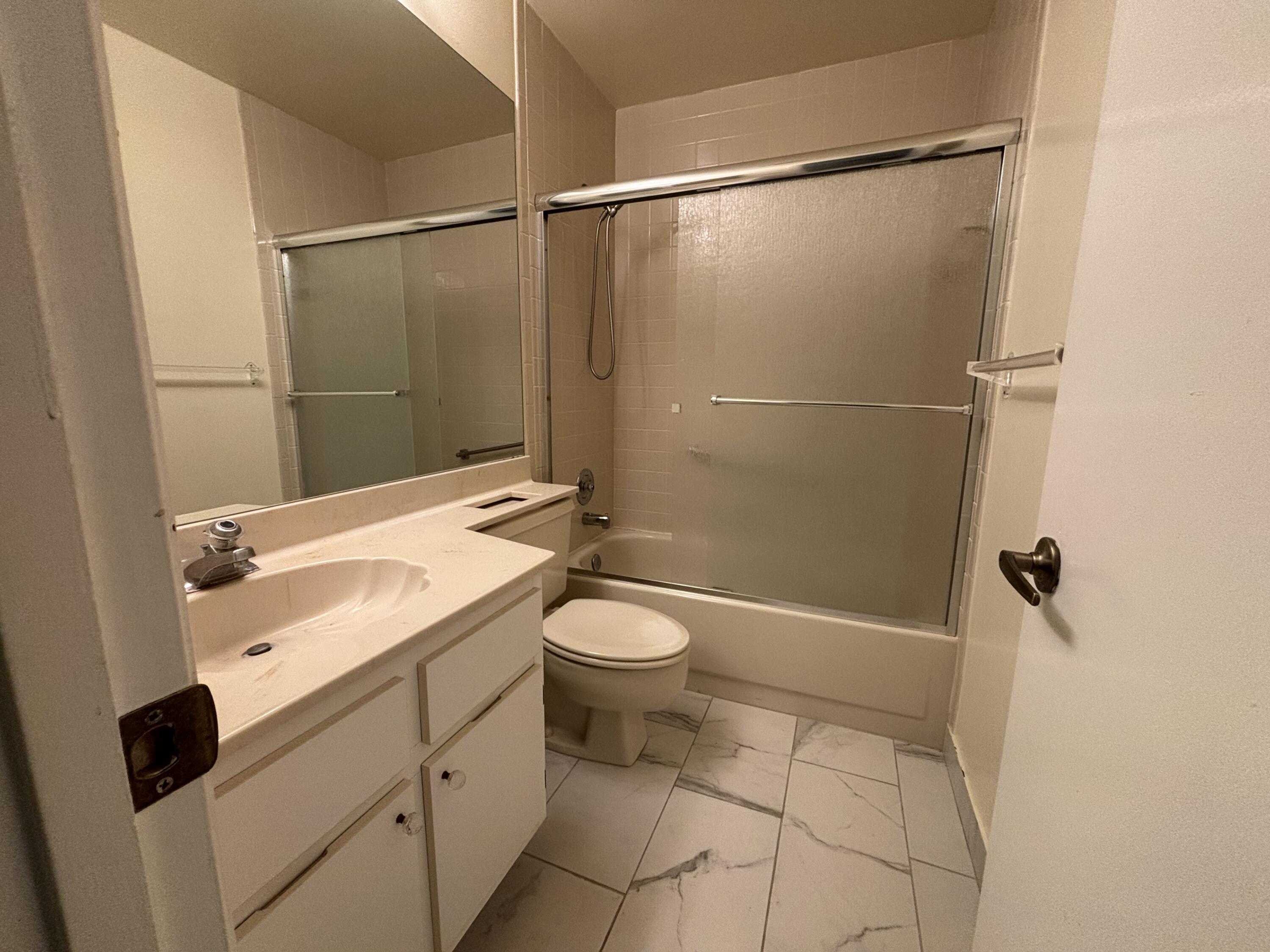 3872 Vine Trail, Unit D Lake Worth, FL 33467 - Photo 16 of 18 a bathroom with a granite countertop sink toilet and shower