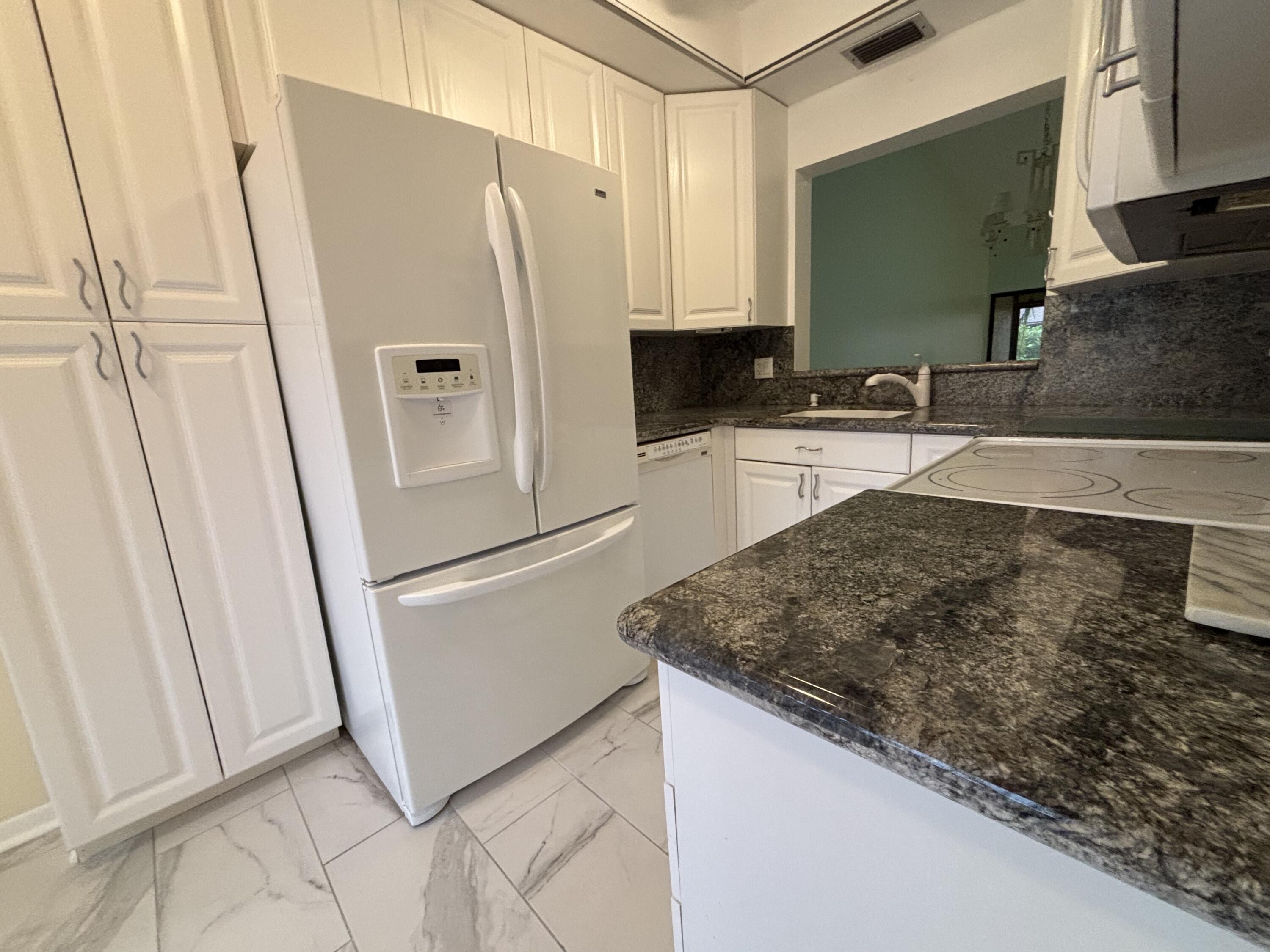 3872 Vine Trail, Unit D Lake Worth, FL 33467 - Photo 3 of 18 a kitchen with stainless steel appliances granite countertop a refrigerator and a sink