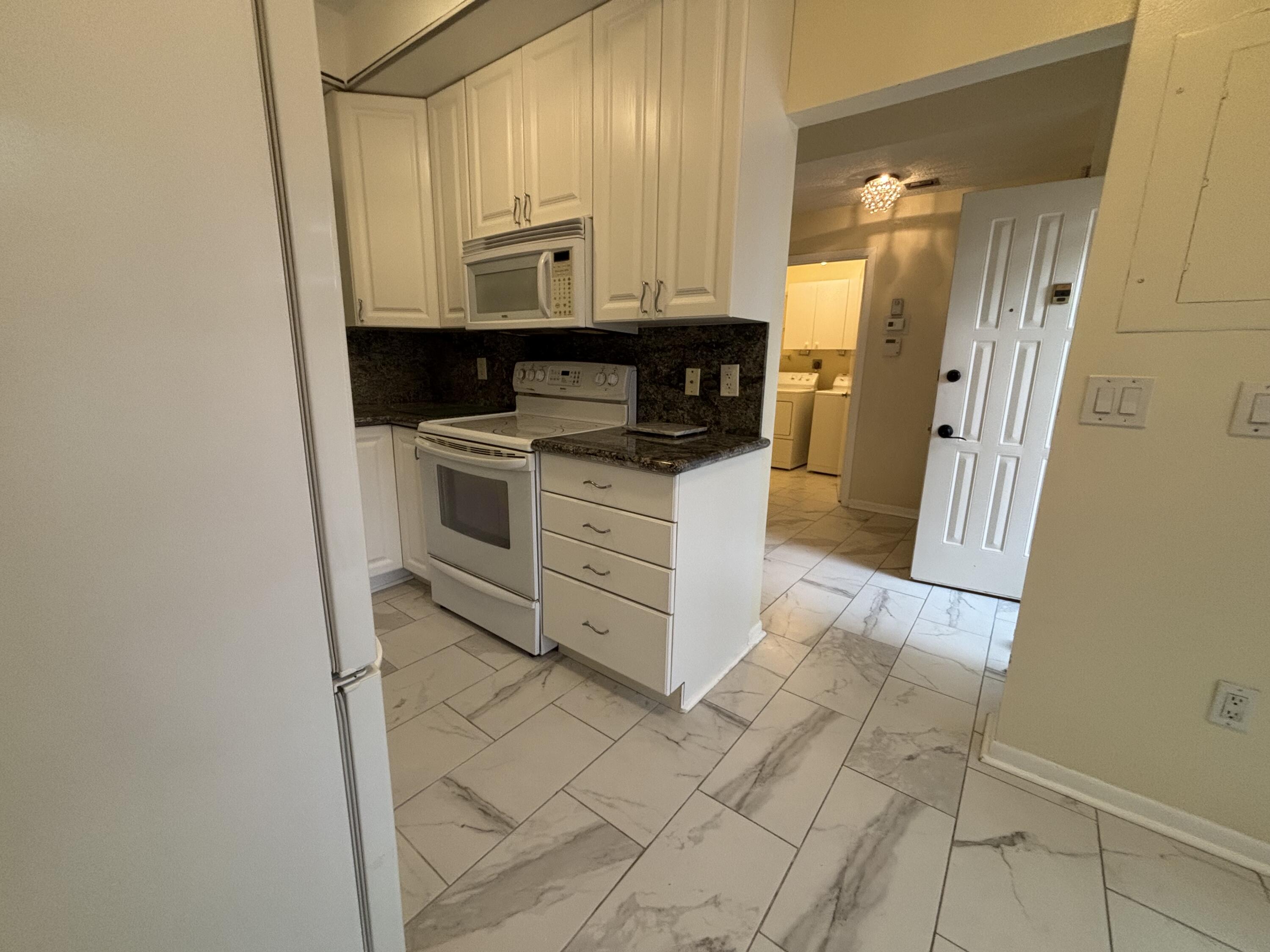 3872 Vine Trail, Unit D Lake Worth, FL 33467 - Photo 4 of 18 a kitchen with stainless steel appliances granite countertop a stove a sink and a refrigerator
