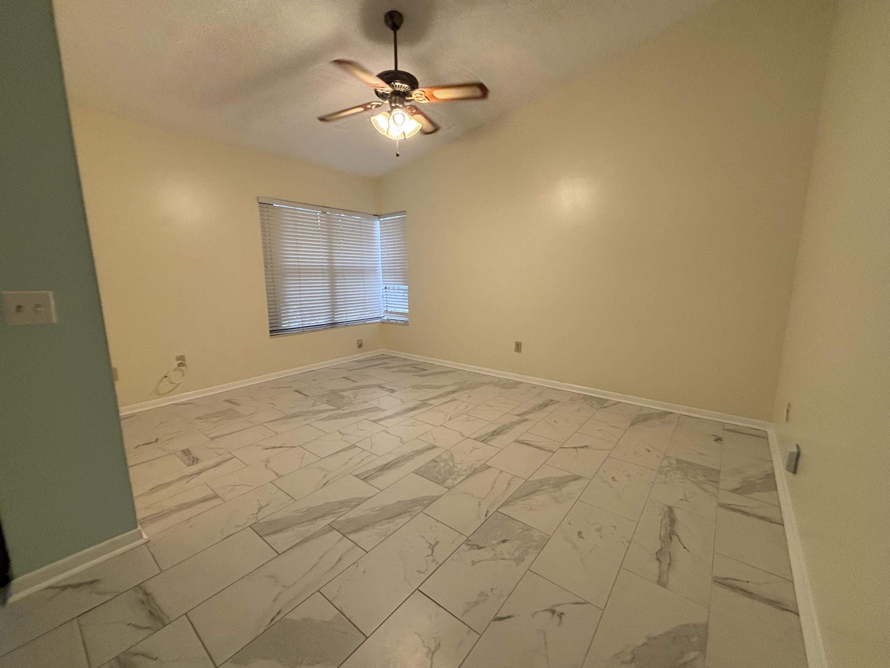 3872 Vine Trail, Unit D Lake Worth, FL 33467 - Photo 9 of 18 an empty room with a chandelier fan and windows