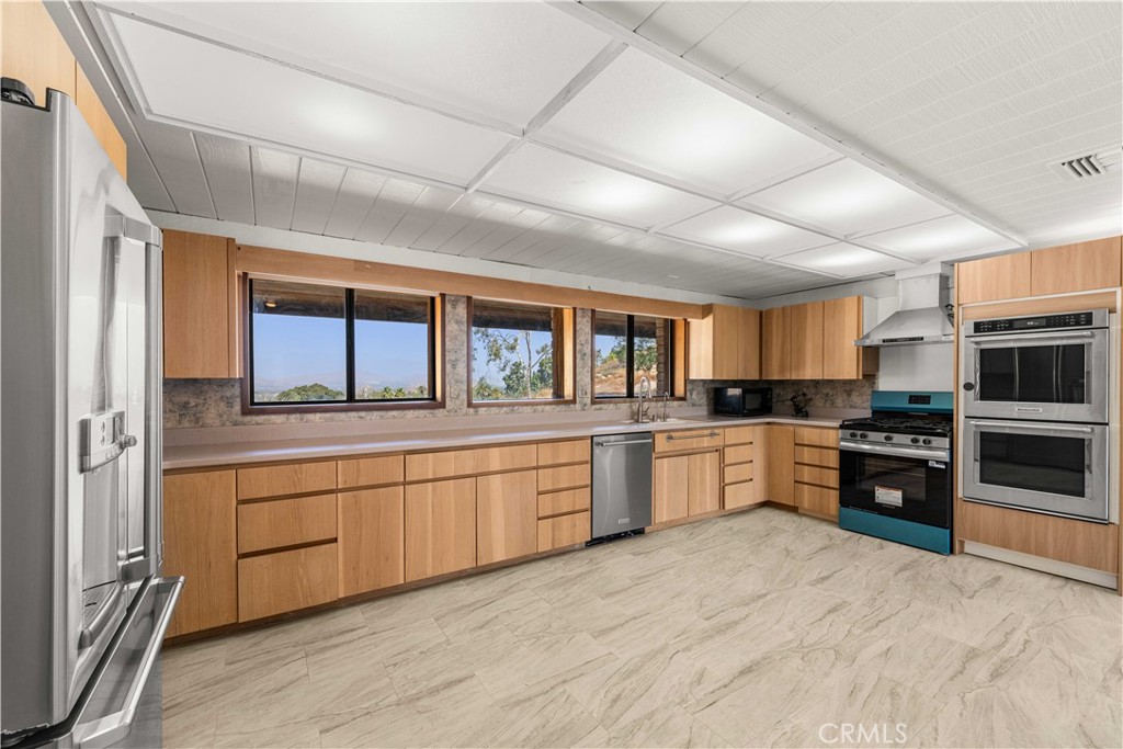 6308 Hawarden Drive Riverside, CA 92506 - Photo 11 of 37 a large kitchen with stainless steel appliances granite countertop a large window and a refrigerator