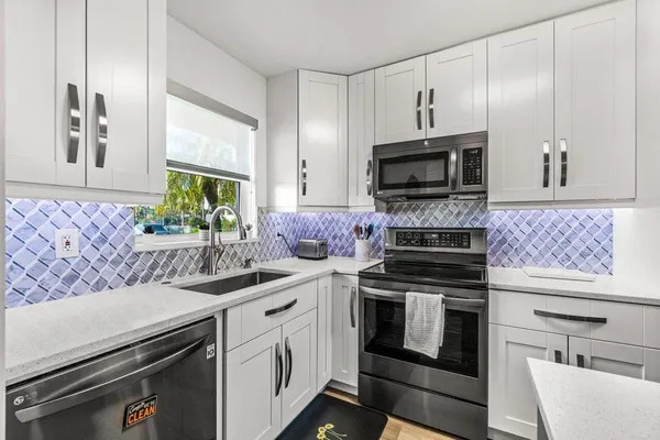 a kitchen with granite countertop a stove sink and microwave