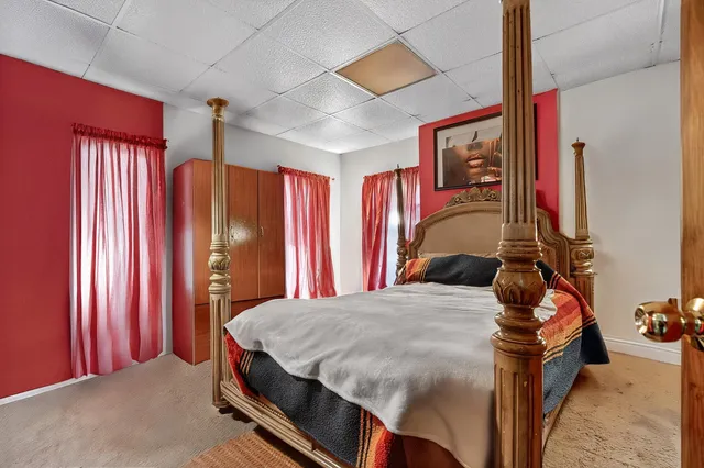 a bedroom with a bed and large windows