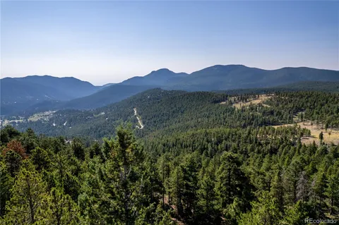 a view of a lush green field with mountains in the background