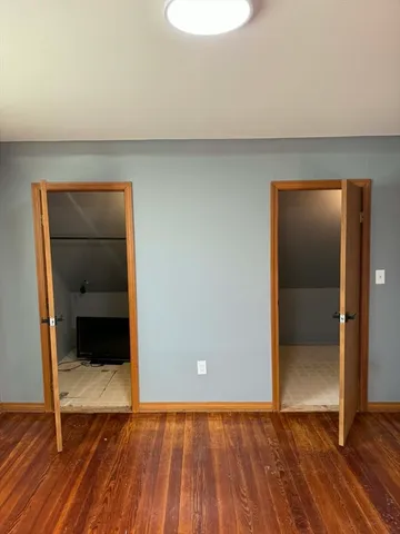 a view of an empty room with wooden floor and closet