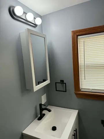 a bathroom with a sink a mirror and a window