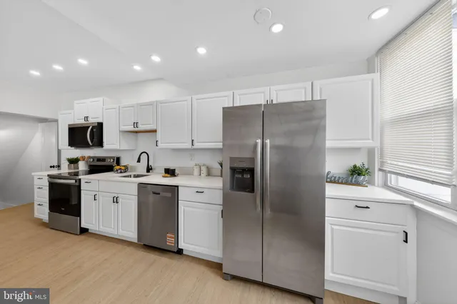 a kitchen with stainless steel appliances a refrigerator sink and white cabinets