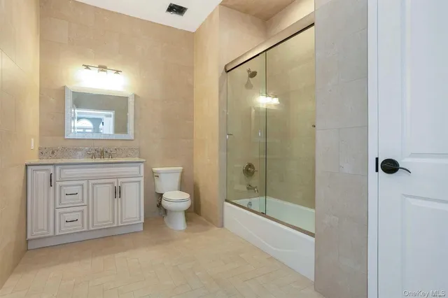 a bathroom with a granite countertop sink a toilet a mirror and shower