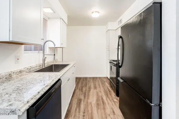 a kitchen with a granite countertop sink refrigerator and cabinets