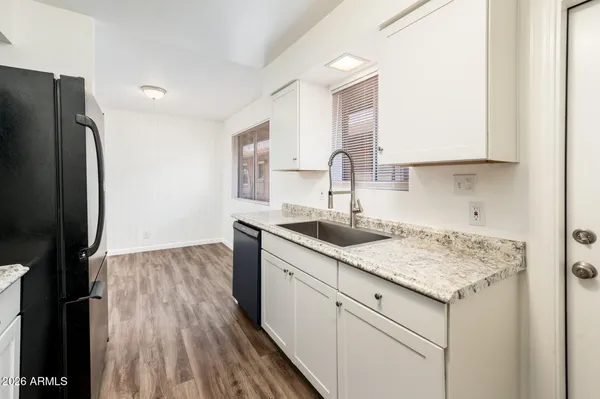 a kitchen with a sink dishwasher and a refrigerator with wooden floor