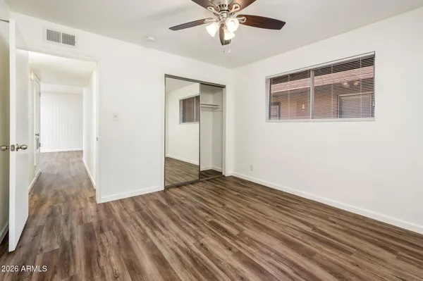 a view of an empty room with wooden floor and a ceiling fan