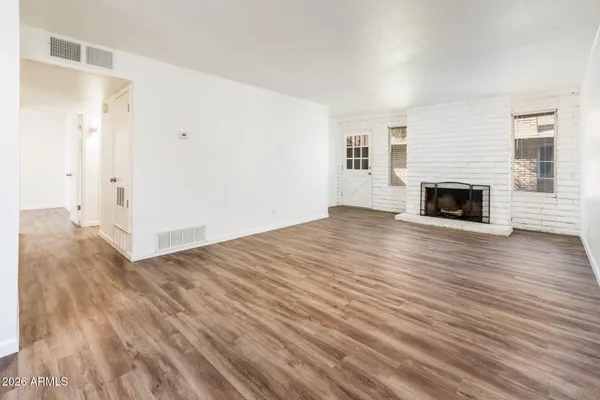 an empty room with wooden floor fireplace and windows