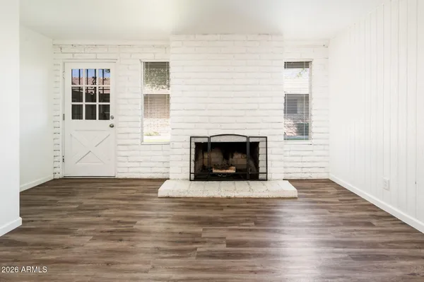 a view of an empty room with wooden floor and a fireplace