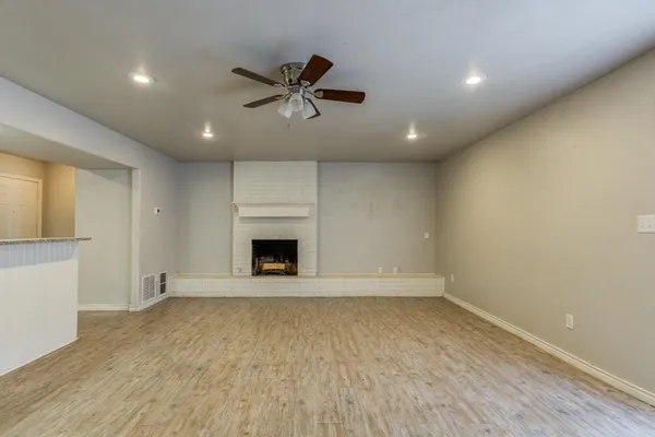 an empty room with chandelier fan and windows
