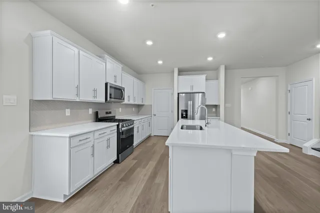 a kitchen with kitchen island a sink stainless steel appliances and white cabinets