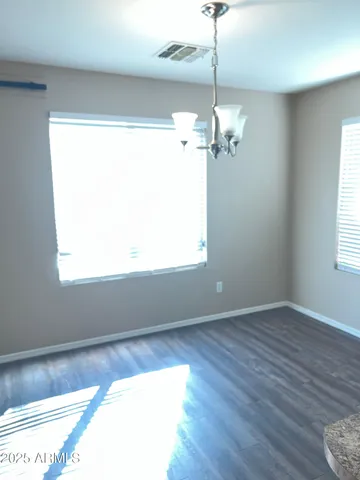 a view of a room with wooden floor chandelier and windows