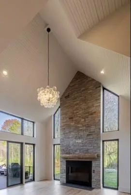 a view of a livingroom with a fireplace a chandelier and windows