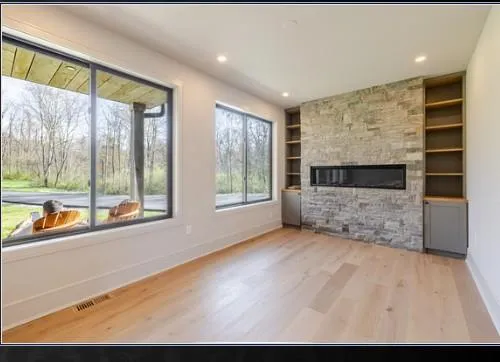 a view of an empty room with a window and fire place