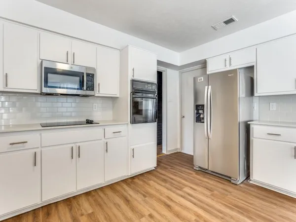 a kitchen with stainless steel appliances white cabinets and wooden floors