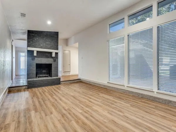 a view of an empty room with wooden floor fireplace and a window