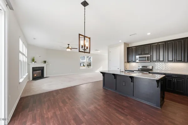 a large kitchen with stainless steel appliances granite countertop a sink dishwasher a stove and white cabinets with wooden floor