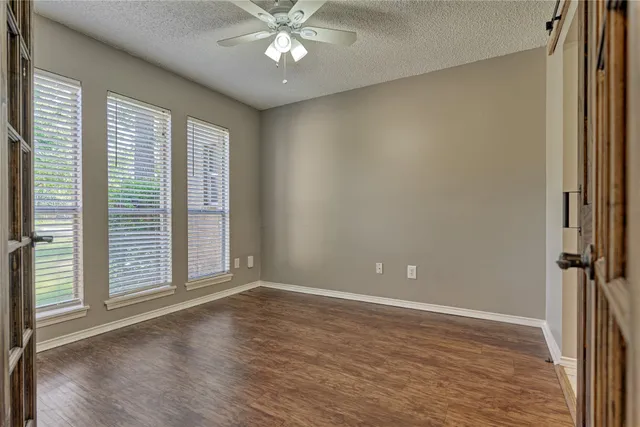a view of an empty room with a window and wooden floor