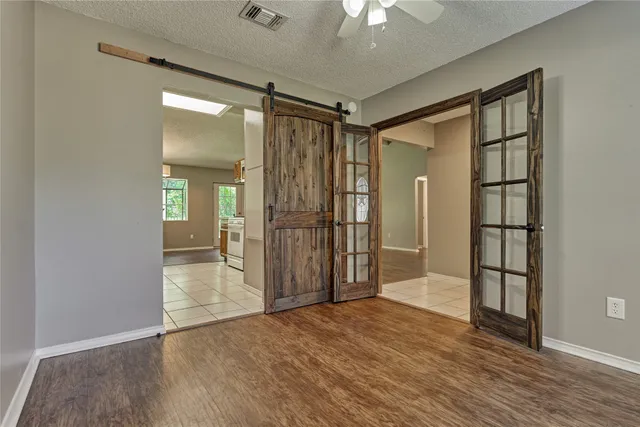 a view of empty room with wooden floor and fan