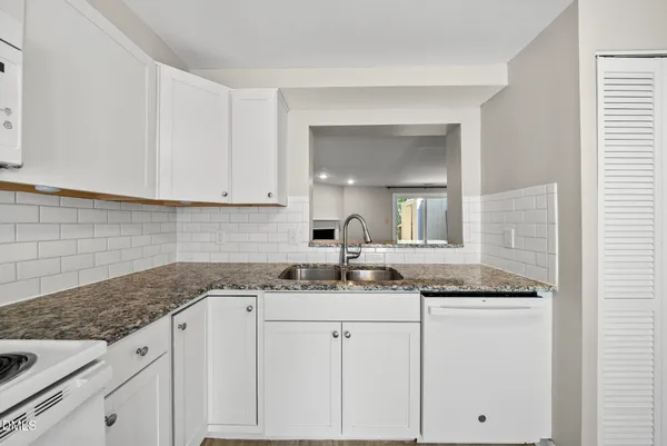 a kitchen with granite countertop white cabinets and white appliances