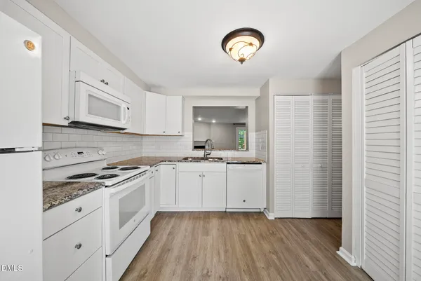 a kitchen with granite countertop white cabinets and white appliances