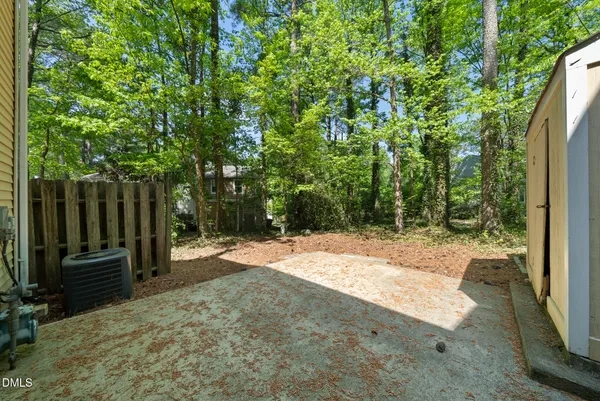 a backyard of a house with lawn chairs plants and large trees