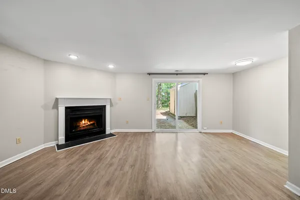 an empty room with wooden floor fire place and windows