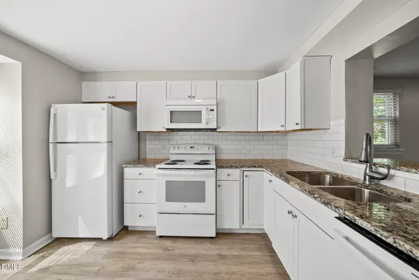 a kitchen with a refrigerator sink and white cabinets