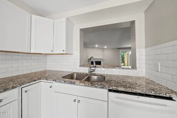 a kitchen with granite countertop white cabinets and a sink