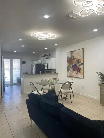 a living room with furniture a refrigerator and kitchen view