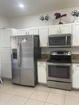 a kitchen with granite countertop a refrigerator and a stove top oven