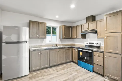 a kitchen with stainless steel appliances granite countertop a stove a sink dishwasher a refrigerator and a microwave