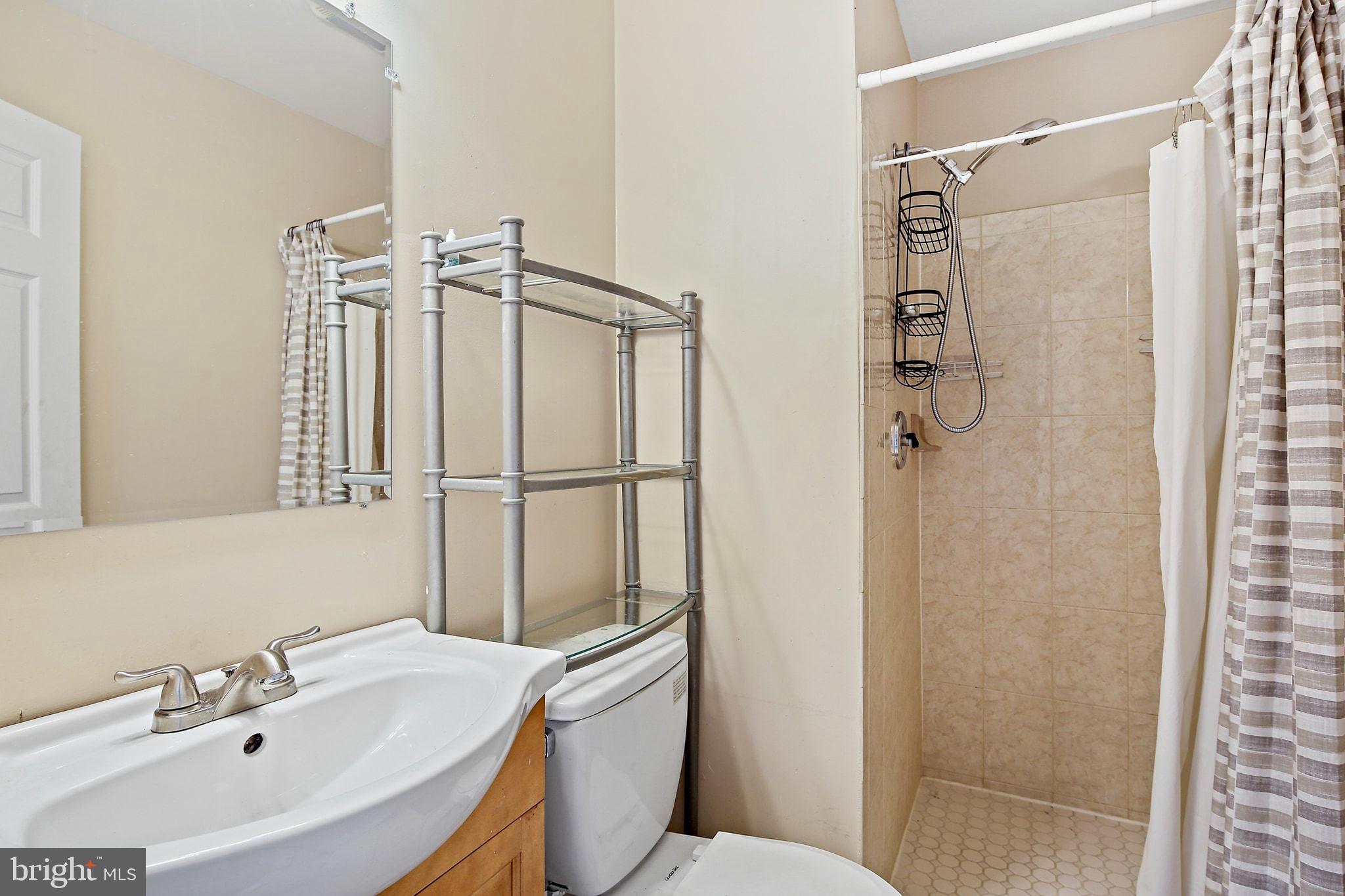 211 North Streeper Street Baltimore, MD 21224 - Photo 23 of 33 a bathroom with a sink a mirror a toilet and shower