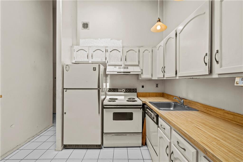 101-06 4th Avenue, Unit 26E Brooklyn, NY 11209 - Photo 6 of 16 a kitchen with white cabinets and white appliances