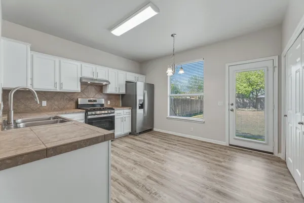 a kitchen with granite countertop a stove a sink and a refrigerator