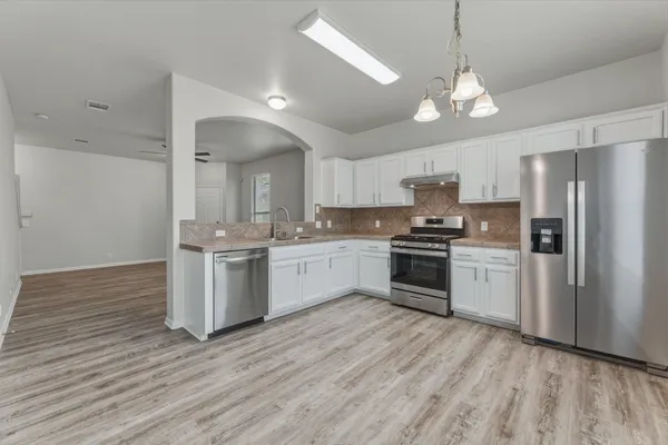 a kitchen with a refrigerator and white cabinets