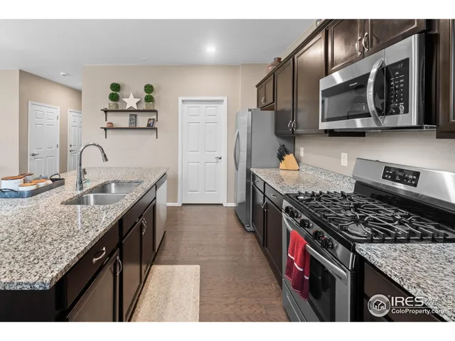 a kitchen with stainless steel appliances granite countertop a stove top oven a sink a refrigerator and dishwasher